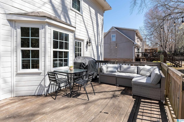 wooden deck with an outdoor living space and area for grilling