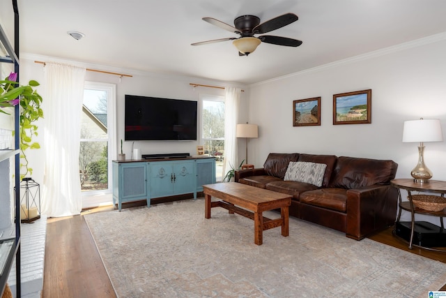 living room featuring light wood-type flooring, ornamental molding, and a ceiling fan