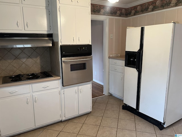 kitchen with oven, under cabinet range hood, white fridge with ice dispenser, light tile patterned flooring, and cooktop