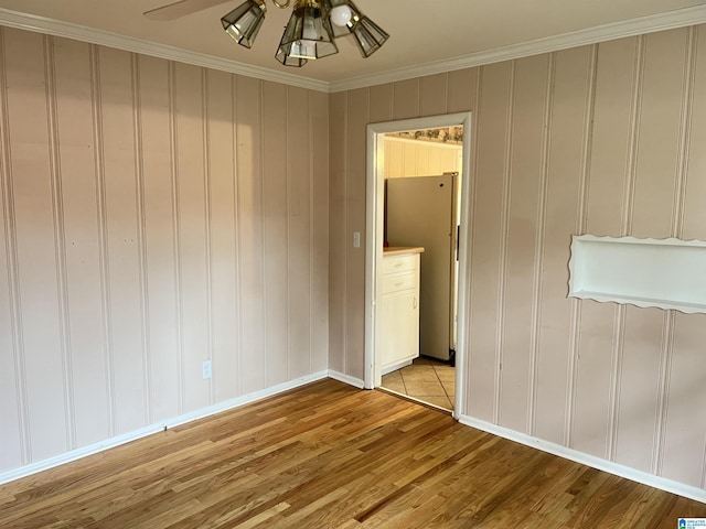 empty room with baseboards, a ceiling fan, crown molding, and light wood finished floors