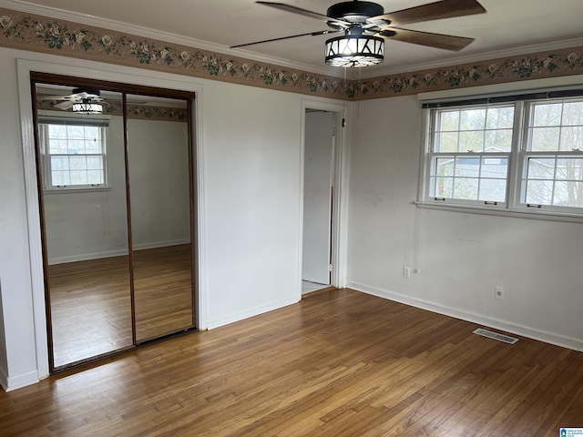 unfurnished bedroom with visible vents, crown molding, baseboards, and wood finished floors