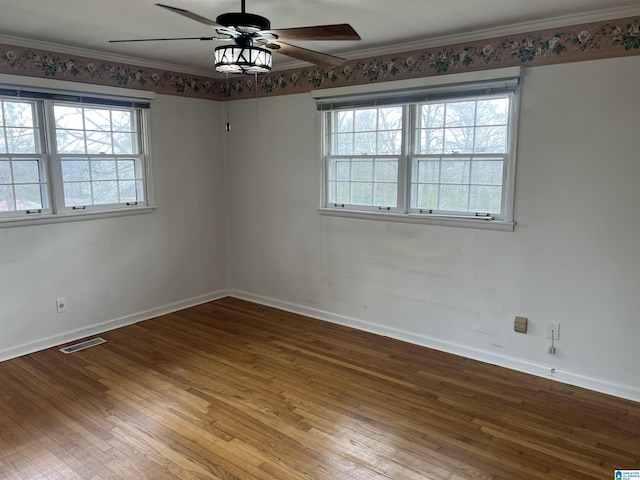 unfurnished room featuring a wealth of natural light, visible vents, hardwood / wood-style floors, and crown molding