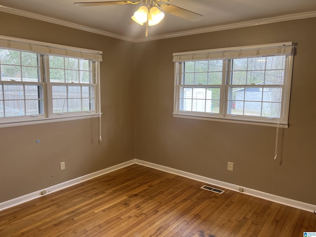 spare room featuring crown molding, hardwood / wood-style flooring, a healthy amount of sunlight, and visible vents