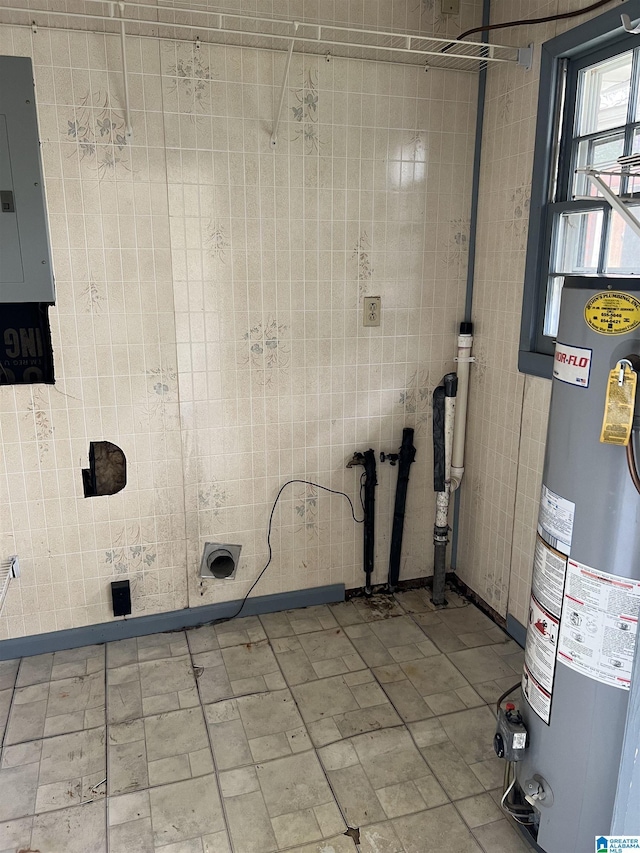 laundry area with water heater, baseboards, tile walls, and electric panel