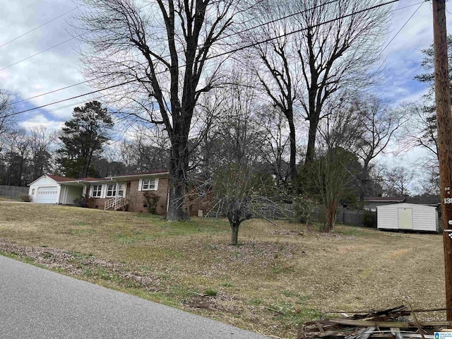 view of front facade with fence, an attached garage, an outdoor structure, a storage unit, and brick siding