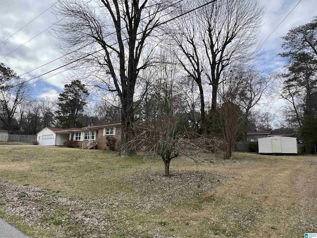 view of front of home featuring a storage unit, an outbuilding, a front yard, and an attached garage