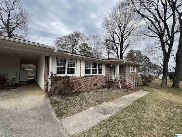 ranch-style house featuring brick siding, a front lawn, a carport, crawl space, and driveway