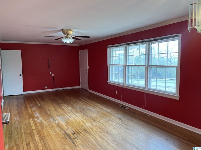 unfurnished room with crown molding, light wood-style floors, visible vents, and baseboards