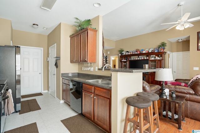 kitchen with a sink, appliances with stainless steel finishes, dark countertops, a kitchen breakfast bar, and open floor plan