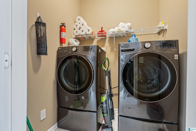 clothes washing area with washer and dryer, baseboards, and laundry area