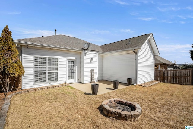 back of property featuring a patio area, a fire pit, a lawn, and fence