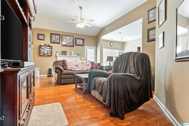 living area with visible vents, light wood finished floors, baseboards, ceiling fan, and vaulted ceiling