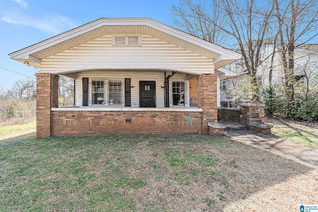 exterior space featuring a front yard, covered porch, and brick siding