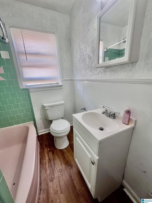 bathroom featuring vanity, wood finished floors, a shower, toilet, and a bathtub