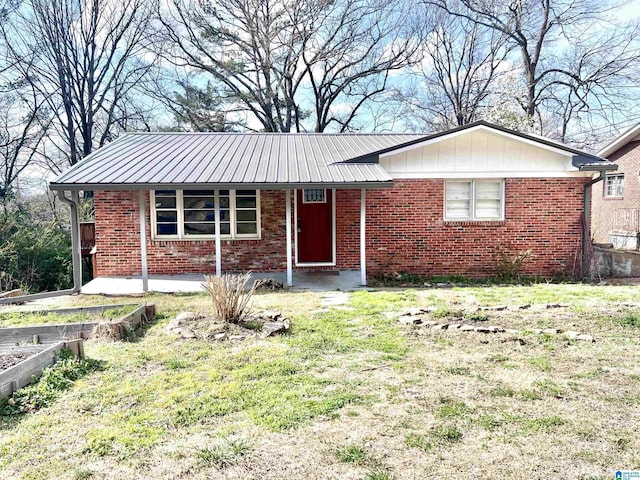 single story home featuring a garden, metal roof, and brick siding