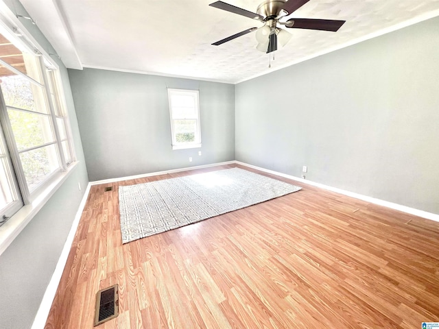 spare room featuring light wood-type flooring, visible vents, plenty of natural light, and baseboards