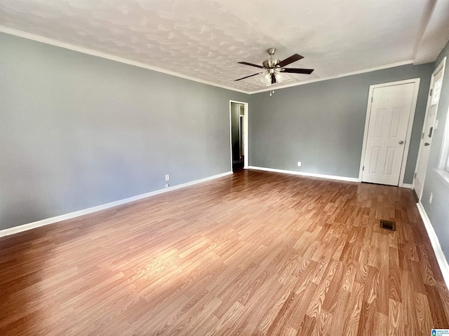 empty room with visible vents, ceiling fan, baseboards, ornamental molding, and wood finished floors