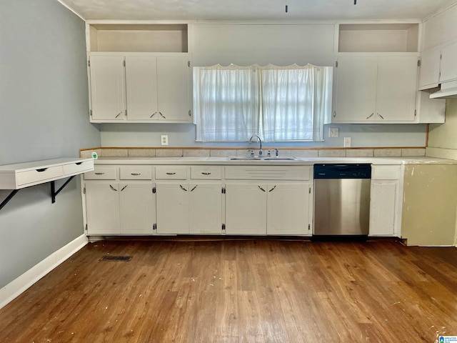 kitchen featuring dark wood finished floors, light countertops, stainless steel dishwasher, white cabinetry, and a sink