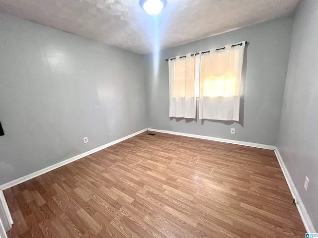 spare room with wood finished floors and baseboards