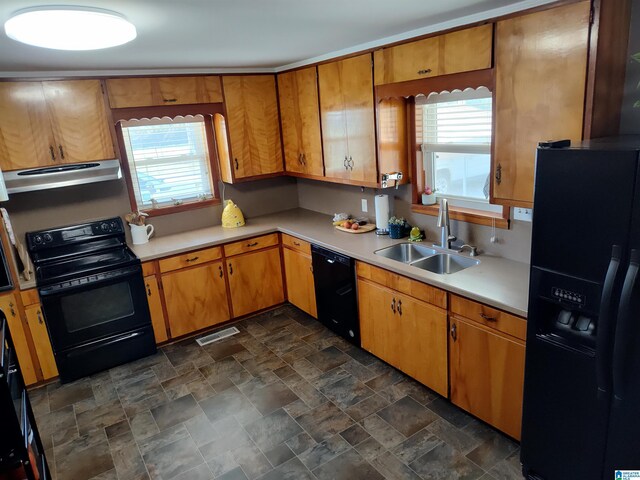 kitchen with stone finish flooring, light countertops, exhaust hood, black appliances, and a sink