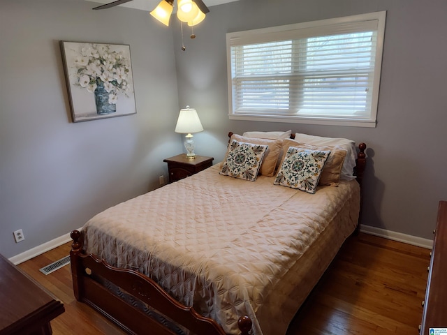 bedroom featuring a ceiling fan, visible vents, wood finished floors, and baseboards