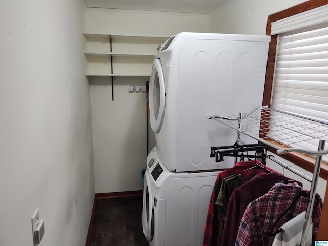 clothes washing area featuring baseboards, stacked washer and clothes dryer, and laundry area