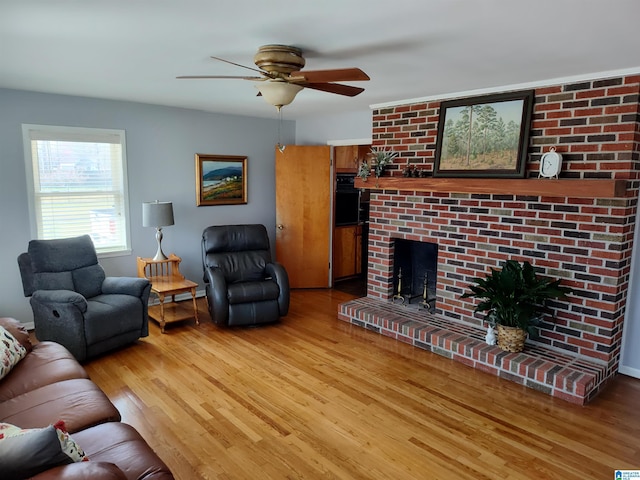 living area with a fireplace, light wood-style floors, and ceiling fan