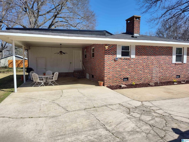 rear view of property featuring crawl space, a chimney, and concrete driveway