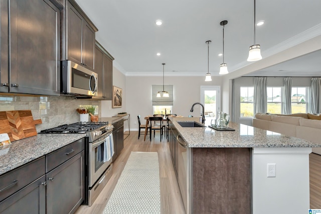 kitchen with ornamental molding, a sink, appliances with stainless steel finishes, decorative backsplash, and dark brown cabinets