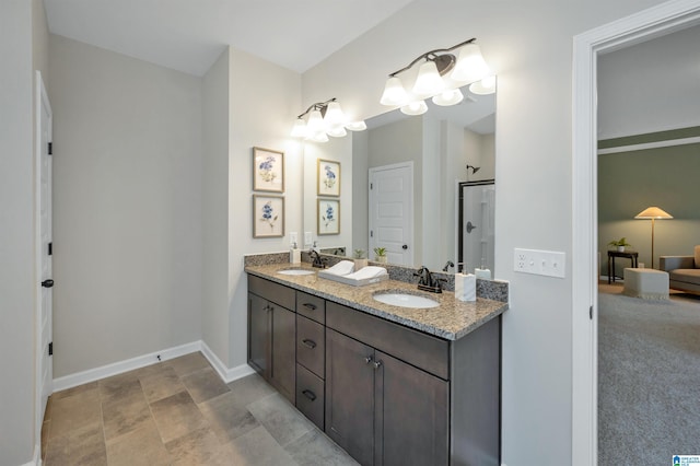 full bathroom featuring double vanity, a shower with shower door, baseboards, and a sink