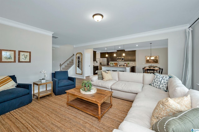 living room featuring visible vents, crown molding, baseboards, a chandelier, and stairs