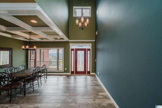 entryway with an inviting chandelier, wood finished floors, baseboards, and coffered ceiling