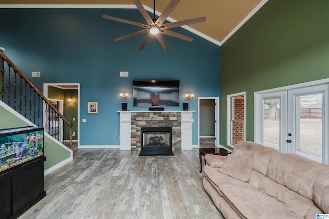 living area with baseboards, stairs, a fireplace, wood finished floors, and high vaulted ceiling