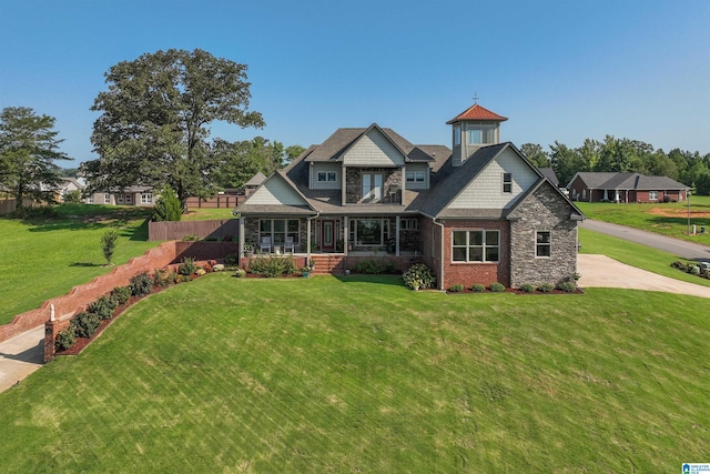 view of front of house featuring stone siding, a porch, a front lawn, and fence