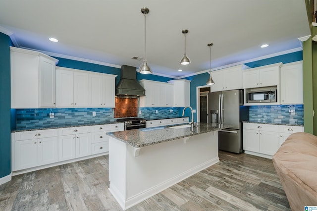 kitchen with premium range hood, ornamental molding, appliances with stainless steel finishes, light wood-style floors, and a sink