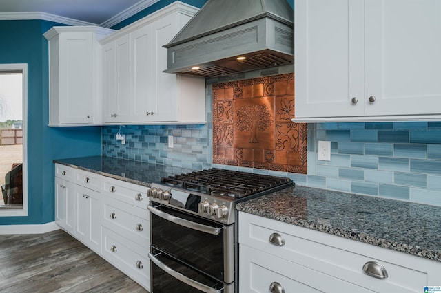 kitchen featuring dark stone countertops, white cabinets, custom range hood, and range with two ovens