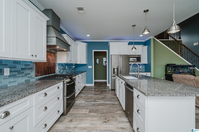 kitchen featuring premium range hood, light wood-type flooring, ornamental molding, stainless steel appliances, and a sink