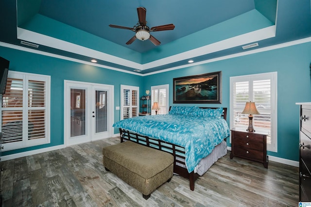 bedroom featuring a tray ceiling, wood finished floors, and visible vents