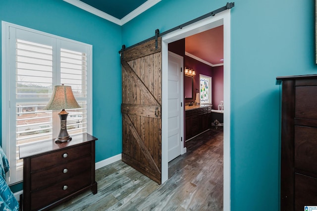 interior space featuring a barn door, wood finished floors, baseboards, and ornamental molding