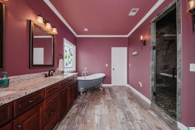 bathroom with ornamental molding, wood finished floors, a stall shower, and a sink