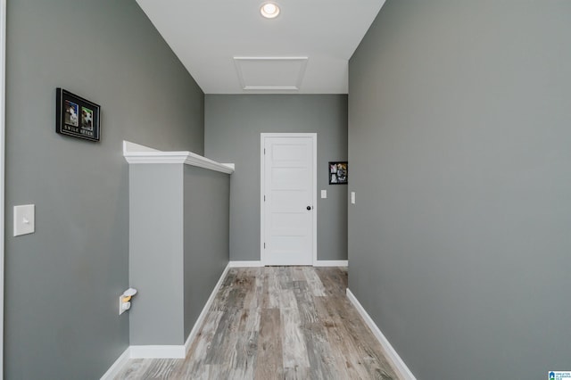 hall with attic access, light wood-style floors, and baseboards