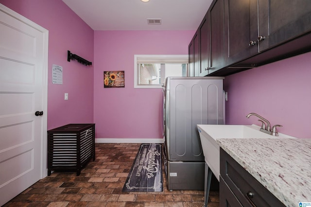 laundry room featuring baseboards, visible vents, washer / dryer, cabinet space, and brick floor