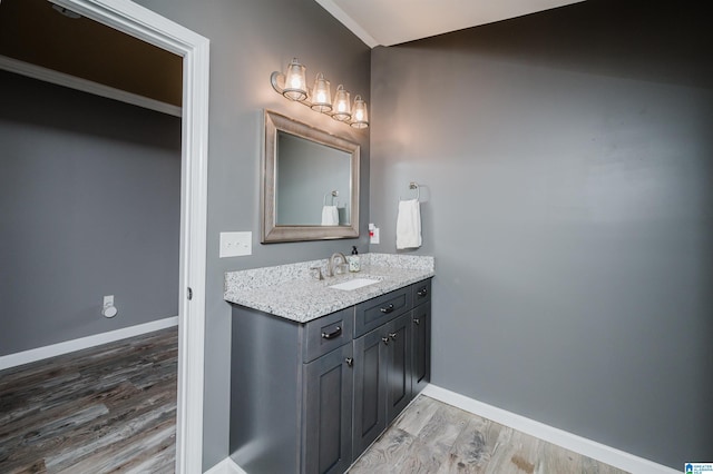 bathroom with baseboards, wood finished floors, and vanity