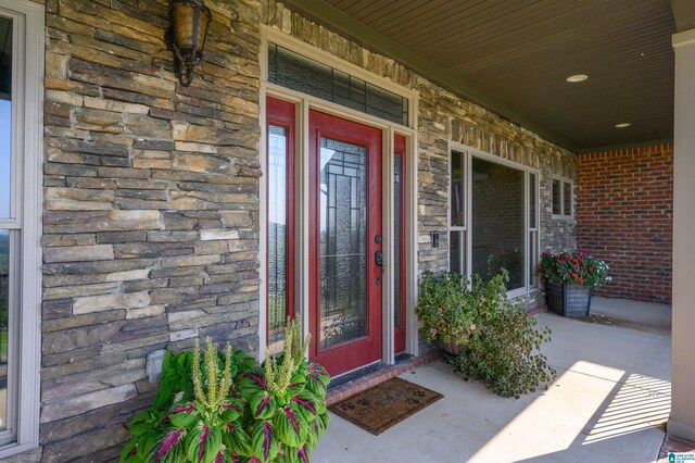 property entrance featuring stone siding, brick siding, and a porch