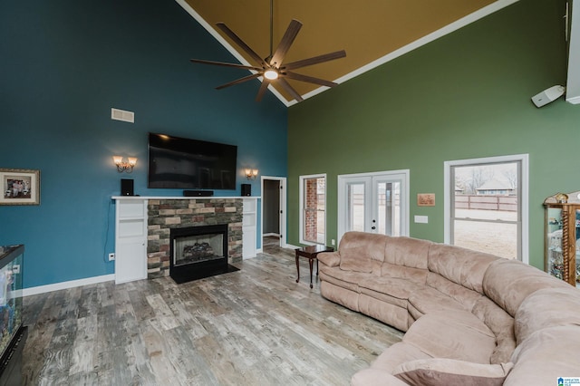 living area featuring a ceiling fan, wood finished floors, french doors, a fireplace, and baseboards