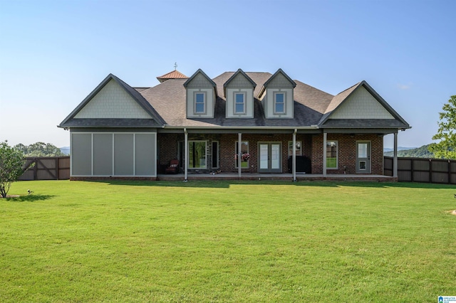 rear view of house featuring french doors, a lawn, brick siding, and fence