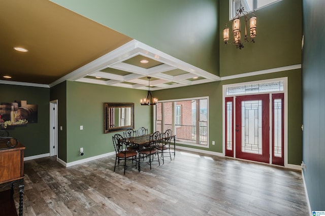 dining room featuring beamed ceiling, coffered ceiling, wood finished floors, baseboards, and a chandelier