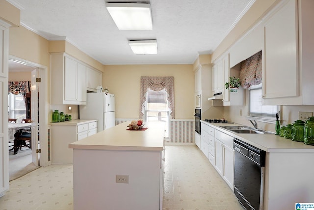 kitchen featuring a center island, light floors, ornamental molding, black appliances, and a sink