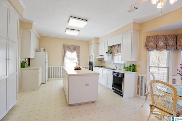 kitchen featuring white cabinetry, black appliances, a center island, and crown molding