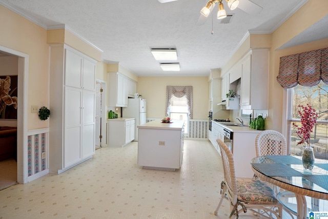 kitchen with white cabinets, a center island, freestanding refrigerator, and light countertops